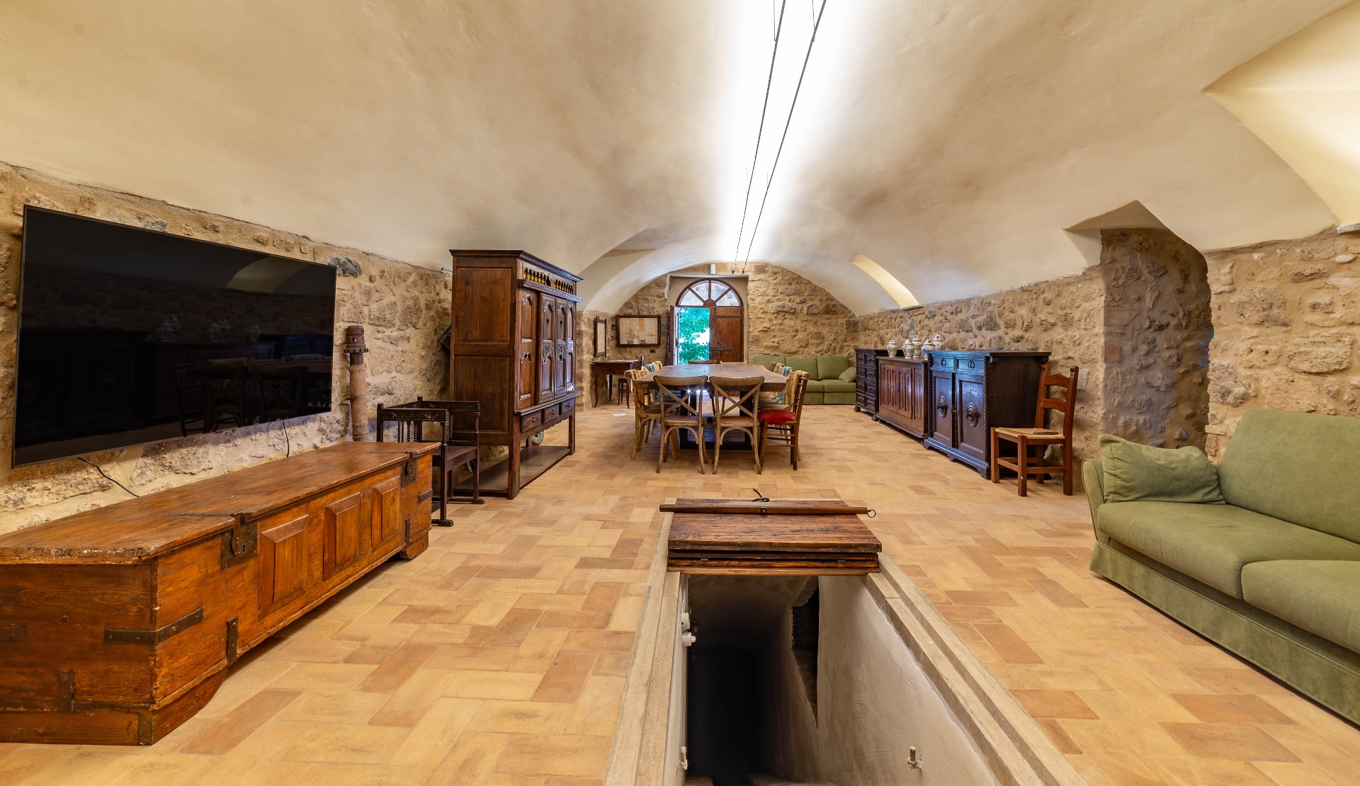 The vaulted stone main hall with the long walnut table, and the twin LED lines running along the vault